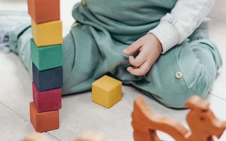 toddler playing independently with natural wood blocks